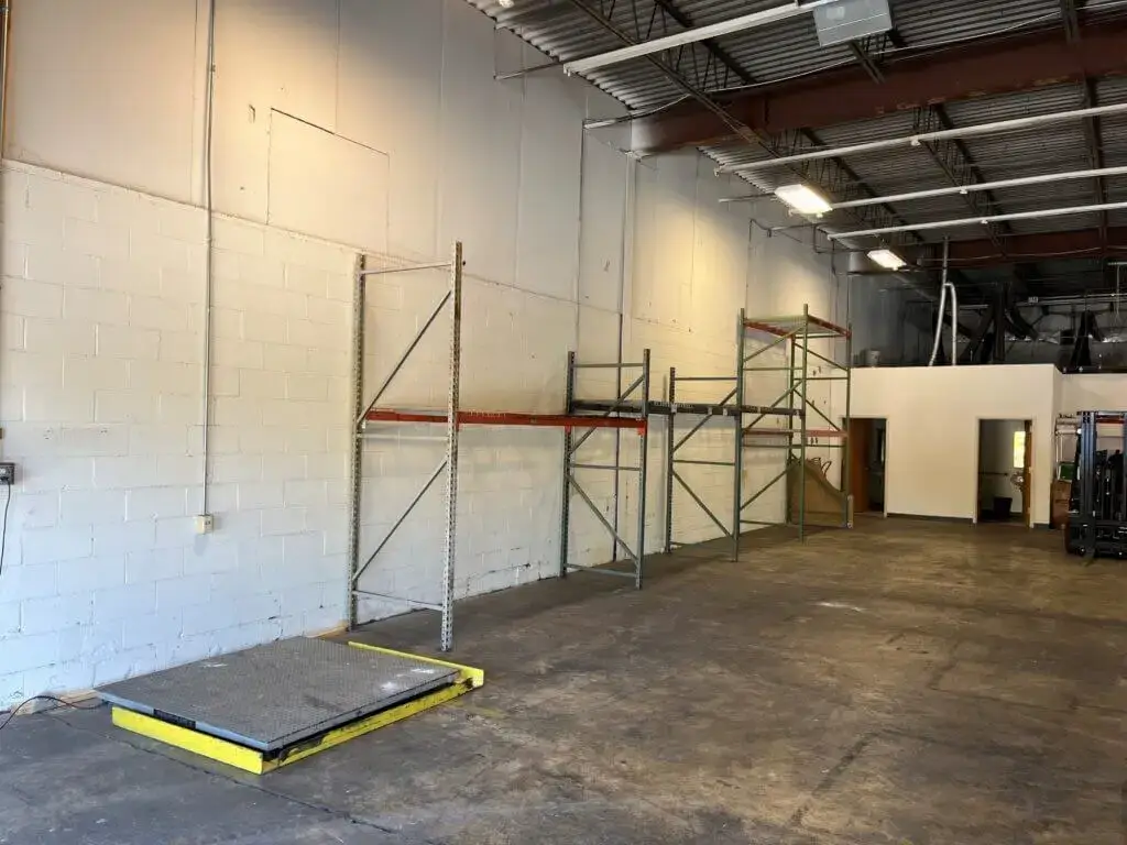 Jade International Expands Warehouse Operations 6 Jade International warehouse interior showing open floor space, pallet racking frames, a floor scale, and a forklift, representing their flexible warehousing and freight consolidation services.