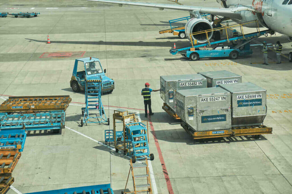 Airport Ground Crew Loading Air Freight Containers Onto An Aircraft On The Tarmac