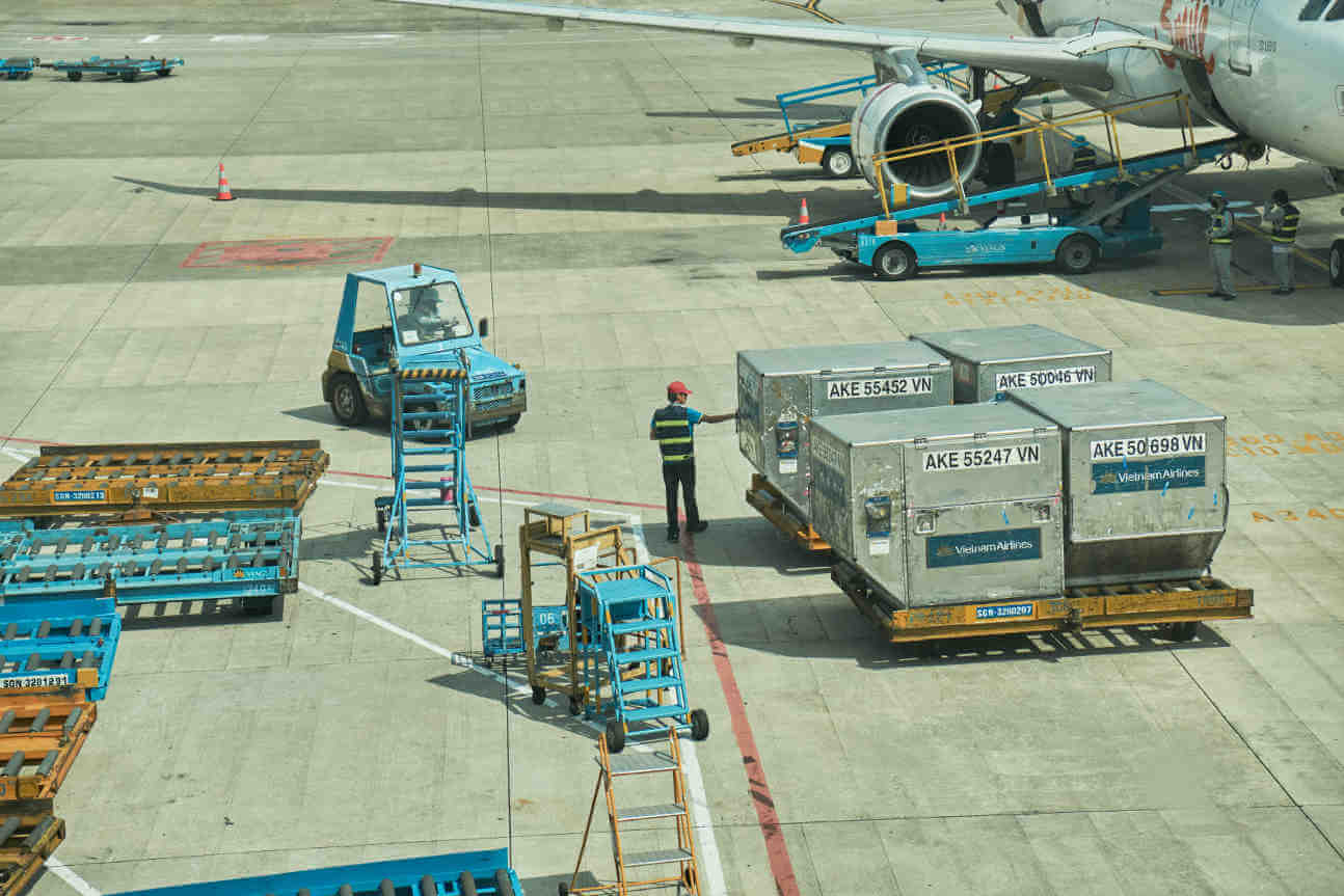 Airport Ground Crew Loading Air Freight Containers Onto An Aircraft On The Tarmac