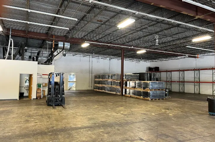Empty retail warehouse space with palletized inventory, shelving racks, and forklift, prepared for storage and distribution operations