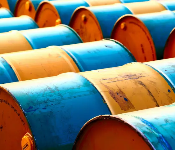 Rows of blue and yellow metal oil drums stacked together in an industrial yard.