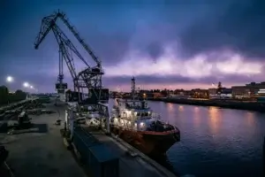 Freight forwarding at a port with cargo vessel and dockside crane at dusk