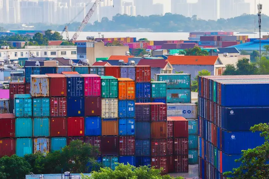 Stacked colorful shipping containers at a port yard, illustrating demurrage and detention fees from delayed cargo pickup.