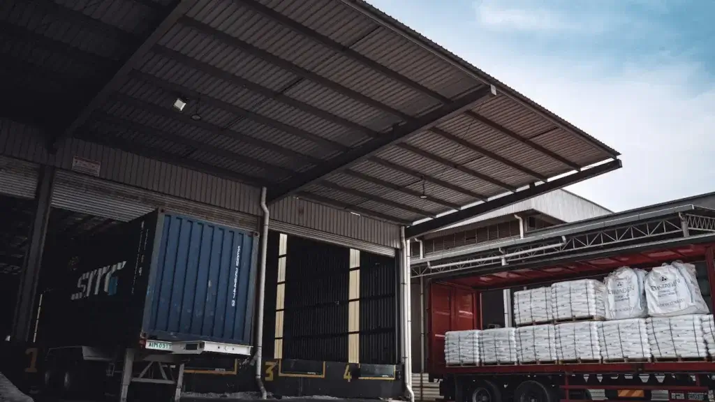 Trucks loading palletized freight at a warehouse dock, representing less-than-truckload shipping and consolidation