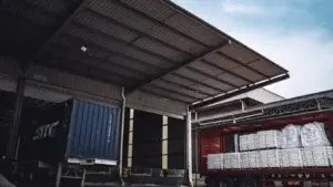 Trucks loading palletized freight at a warehouse dock, representing less-than-truckload shipping and consolidation