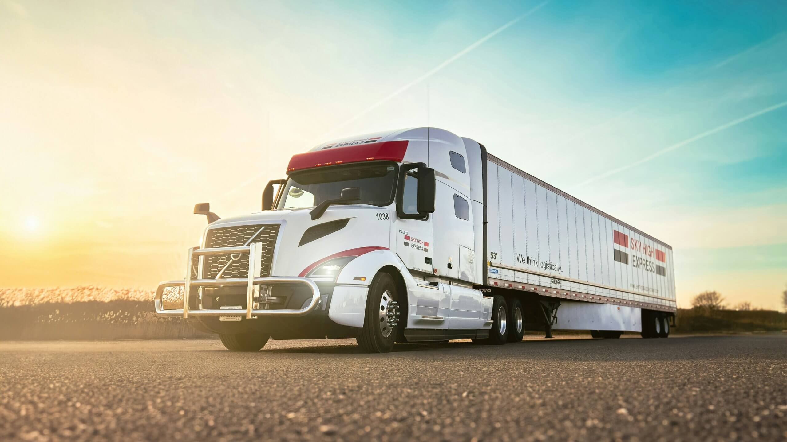 Branded LTL semi-truck and 53-foot trailer on the road at sunset, representing Jade International's less than truckload freight shipping and logistics services.