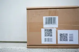 Cardboard package with barcode and QR code labels instead of sender details
