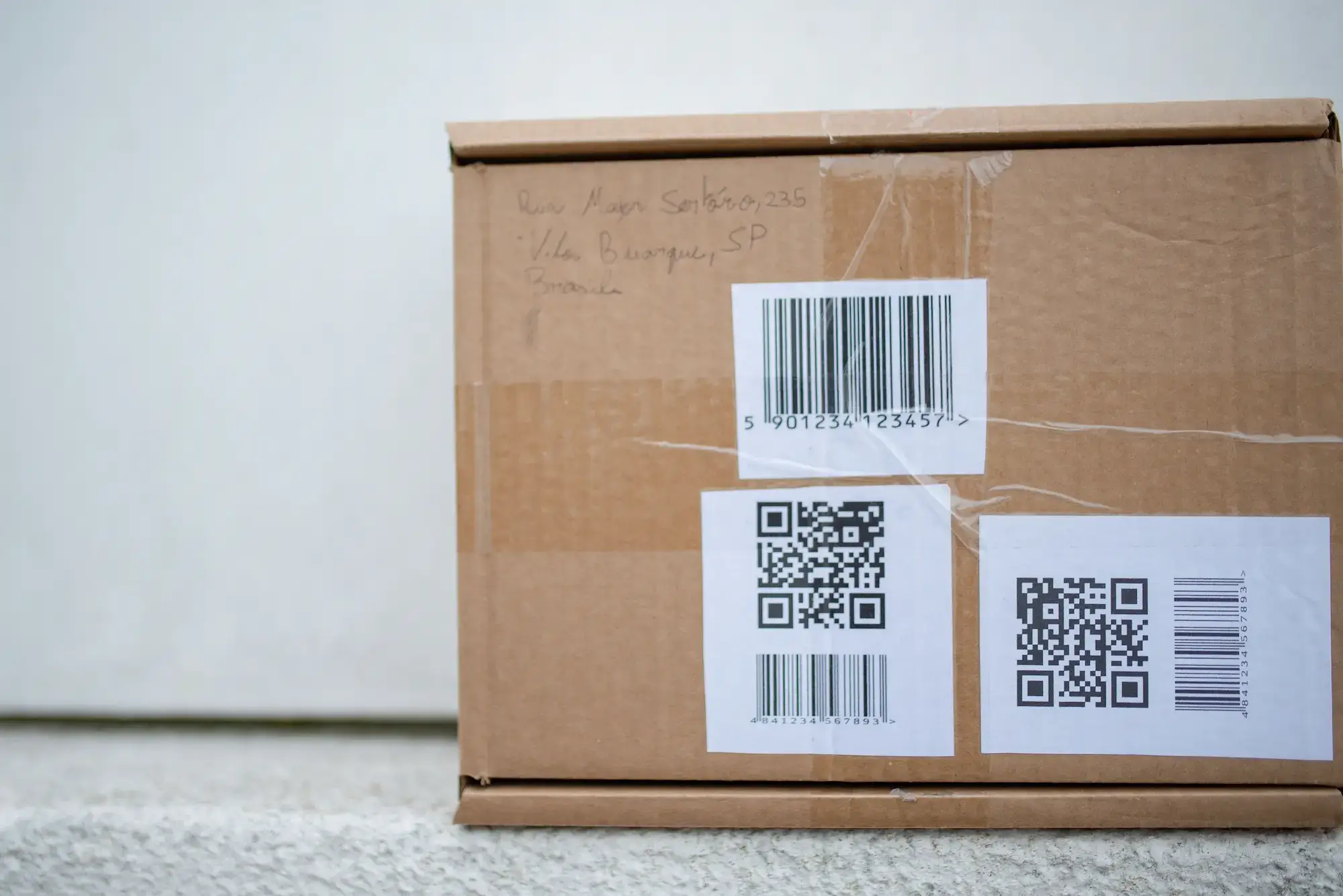 Cardboard package with barcode and QR code labels instead of sender details