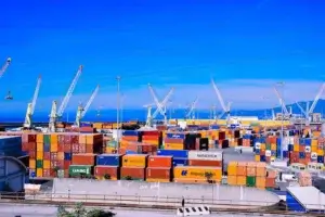 Container ship docked at a busy port with cranes loading shipping containers for freight forwarding