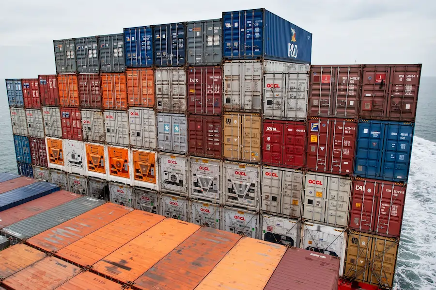 Stacked shipping containers aboard a cargo vessel crossing open sea